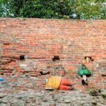 Torun, Podchmurna street, small, colorful characters reading books in front of a red, brick wall